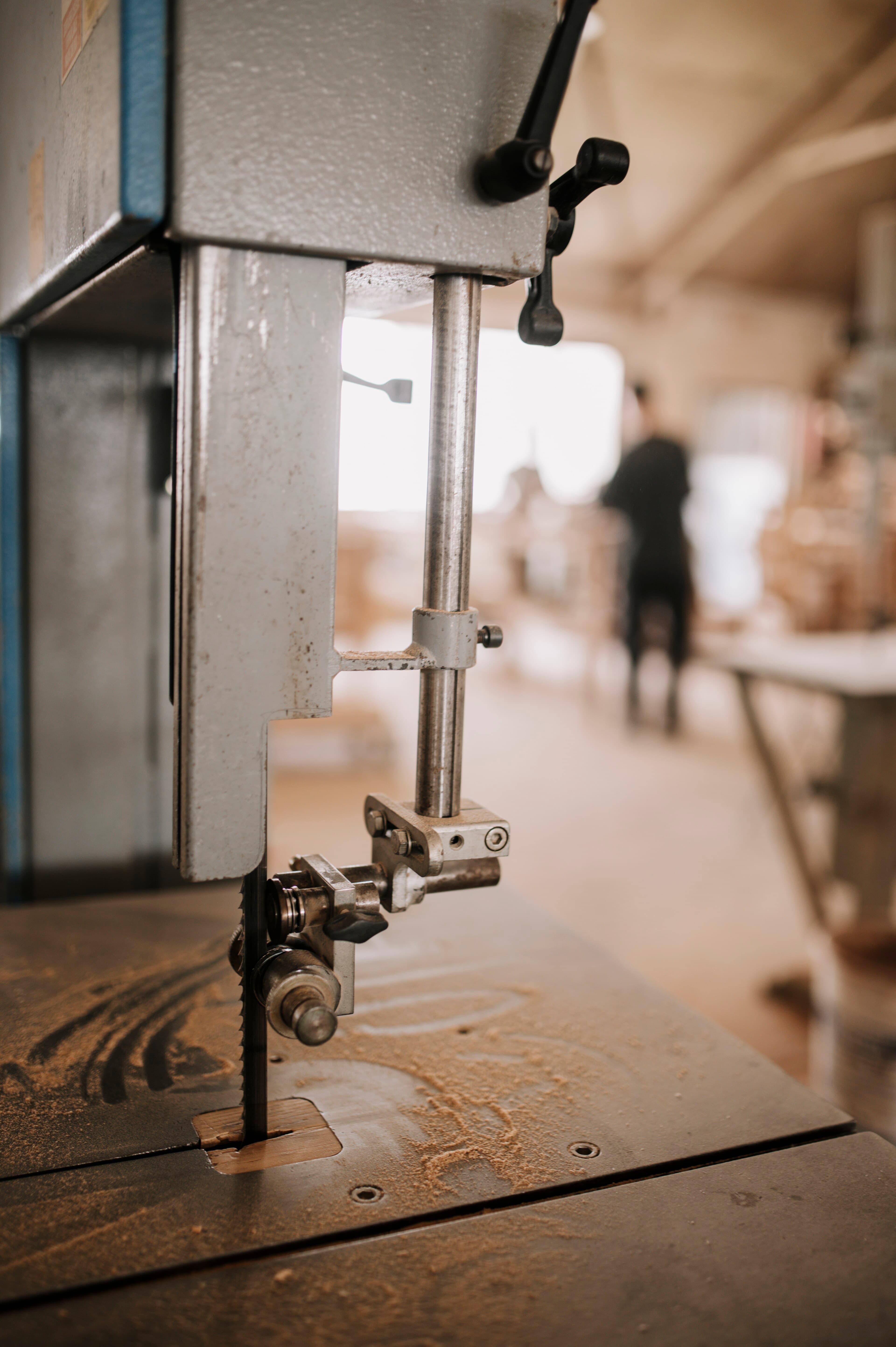 Band saw and timber in a woodworking workshop with craftspeople working